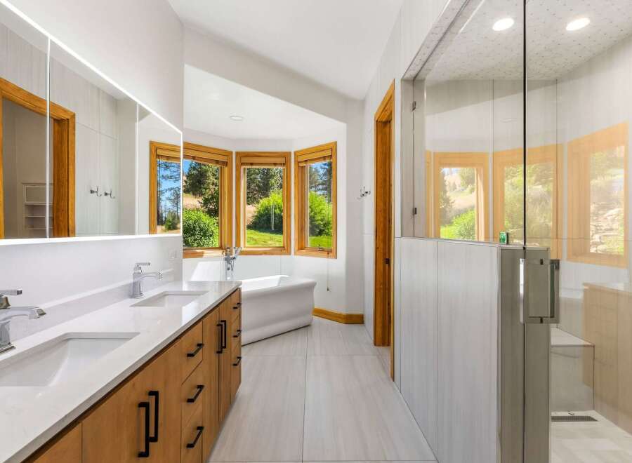 Experience luxury in this stunning bathroom featuring a freestanding bathtub positioned to enjoy scenic views through a bay window.