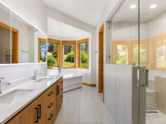 Experience luxury in this stunning bathroom featuring a freestanding bathtub positioned to enjoy scenic views through a bay window.