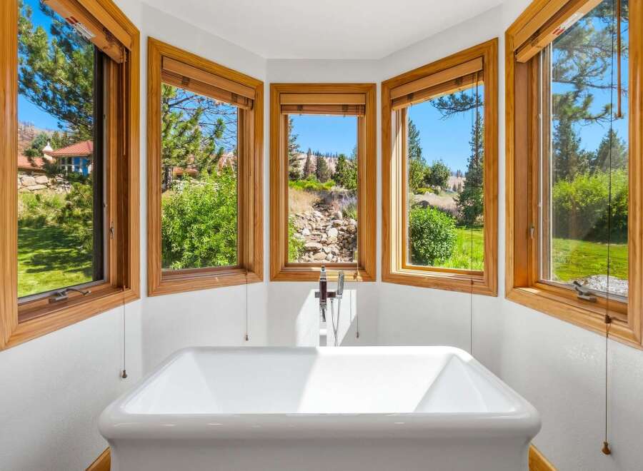 Indulge in ultimate relaxation in this stunning bathroom featuring a freestanding soaking tub perfectly positioned to capture breathtaking views.