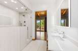 Experience luxury in this modern bathroom featuring a spacious glass-enclosed shower and a sleek double vanity with illuminated mirrors.