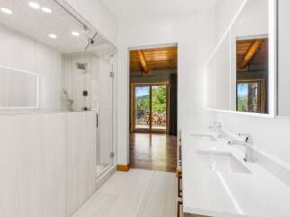 Experience luxury in this modern bathroom featuring a spacious glass-enclosed shower and a sleek double vanity with illuminated mirrors.