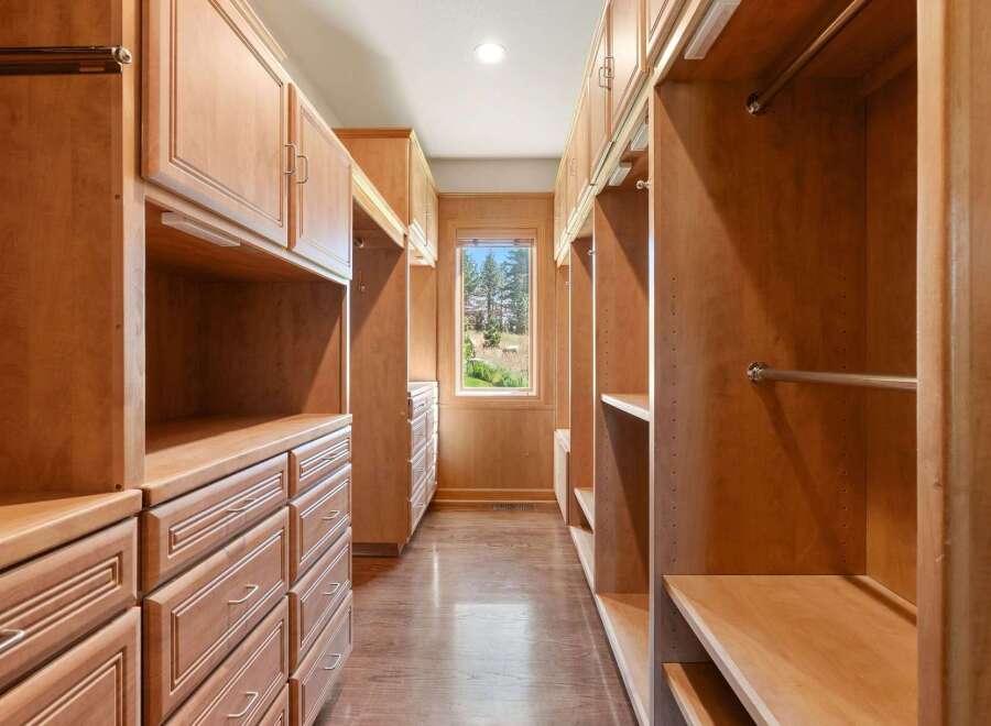 Step into this spacious walk-in closet, featuring custom light wood cabinetry and ample storage solutions.