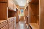 Step into this spacious walk-in closet, featuring custom light wood cabinetry and ample storage solutions.
