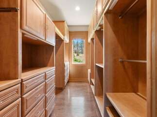 Step into this spacious walk-in closet, featuring custom light wood cabinetry and ample storage solutions.