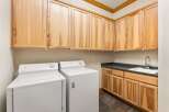 This laundry room features ample storage with light wood cabinetry above and below the countertop.