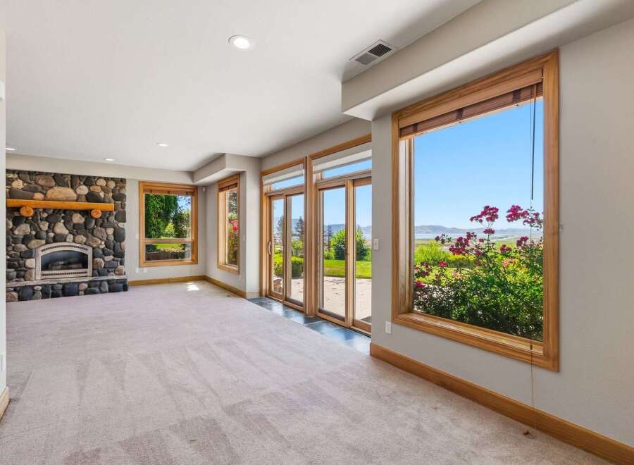 Experience breathtaking views from this spacious living area, featuring a magnificent stone fireplace and expansive windows that frame the stunning landscape.