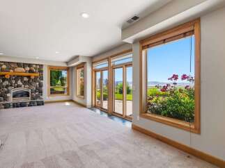 Experience breathtaking views from this spacious living area, featuring a magnificent stone fireplace and expansive windows that frame the stunning landscape.