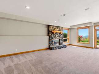Experience breathtaking views from this spacious living area, featuring a stunning stone fireplace with a rustic wooden mantel.