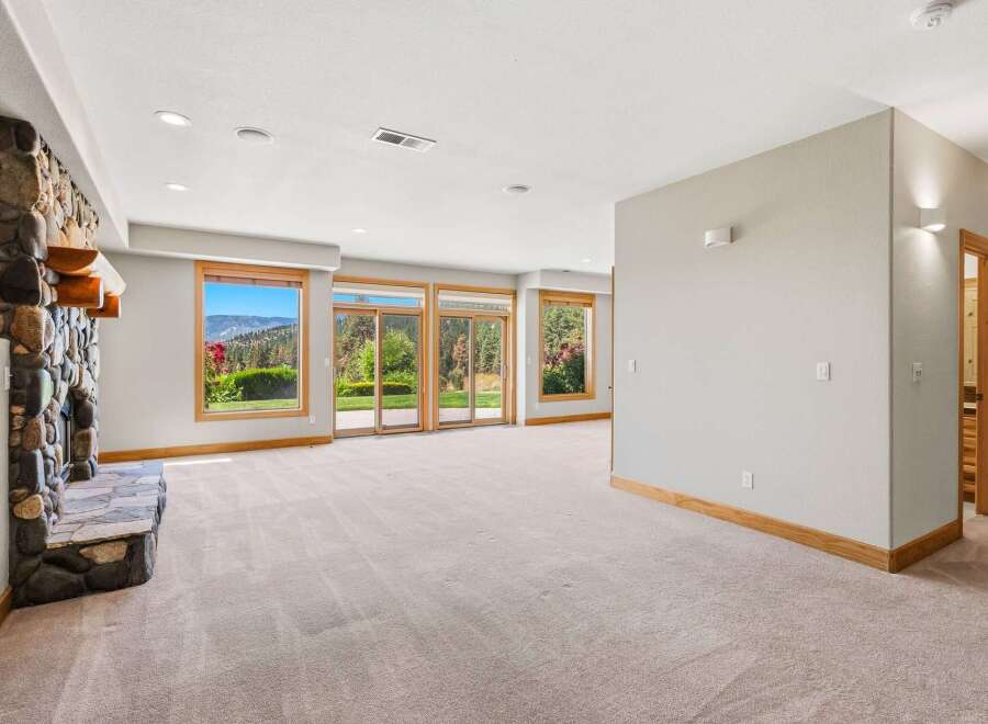 Experience breathtaking mountain views from this spacious living area, featuring a striking stone fireplace and expansive windows that flood the room with natural light.