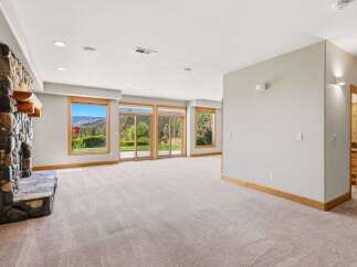 Experience breathtaking mountain views from this spacious living area, featuring a striking stone fireplace and expansive windows that flood the room with natural light.