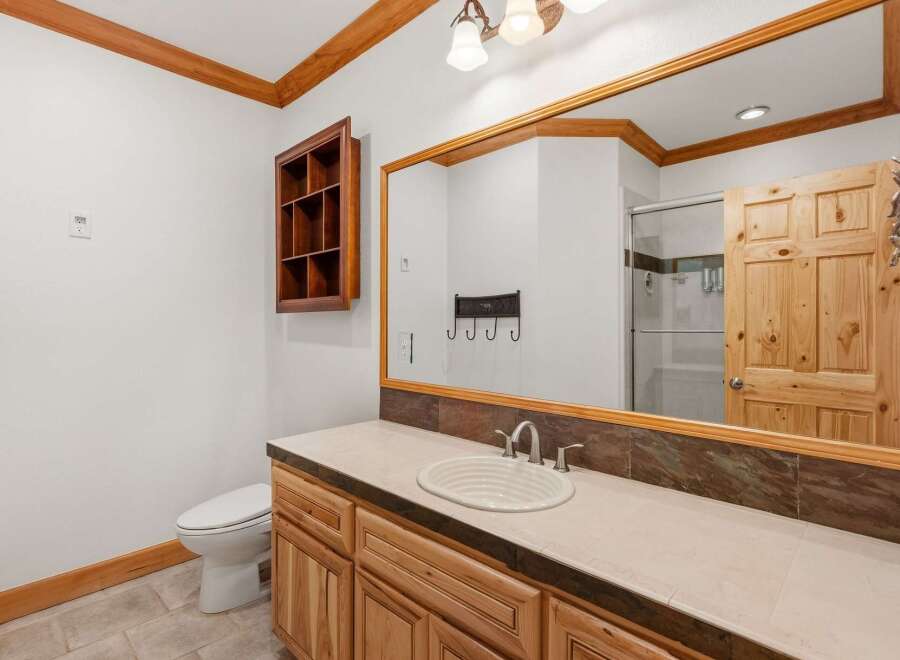 This rustic bathroom features a charming wooden vanity with a light-colored countertop and a white basin sink.