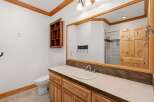 This rustic bathroom features a charming wooden vanity with a light-colored countertop and a white basin sink.