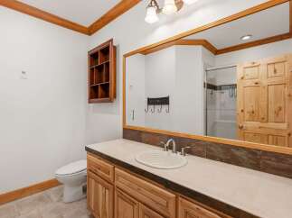 This rustic bathroom features a charming wooden vanity with a light-colored countertop and a white basin sink.