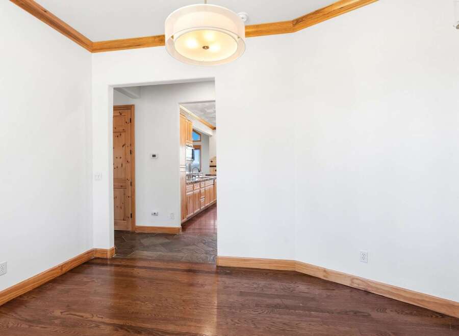 Experience the warmth of this inviting dining area, featuring rich hardwood floors that gleam under a stylish drum pendant light.