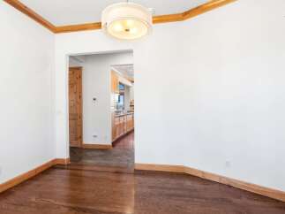 Experience the warmth of this inviting dining area, featuring rich hardwood floors that gleam under a stylish drum pendant light.