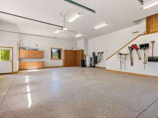 This spacious garage offers ample storage with built-in wooden cabinets and shelving units.