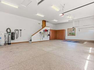 This spacious garage offers ample storage with built-in wooden cabinets and a dedicated area for tools, including shovels, rakes, and brooms.