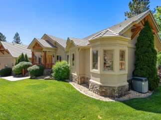 This stunning home features a beautiful stucco exterior with a stone accent base, complemented by a multi-level roofline and exposed wooden beams.