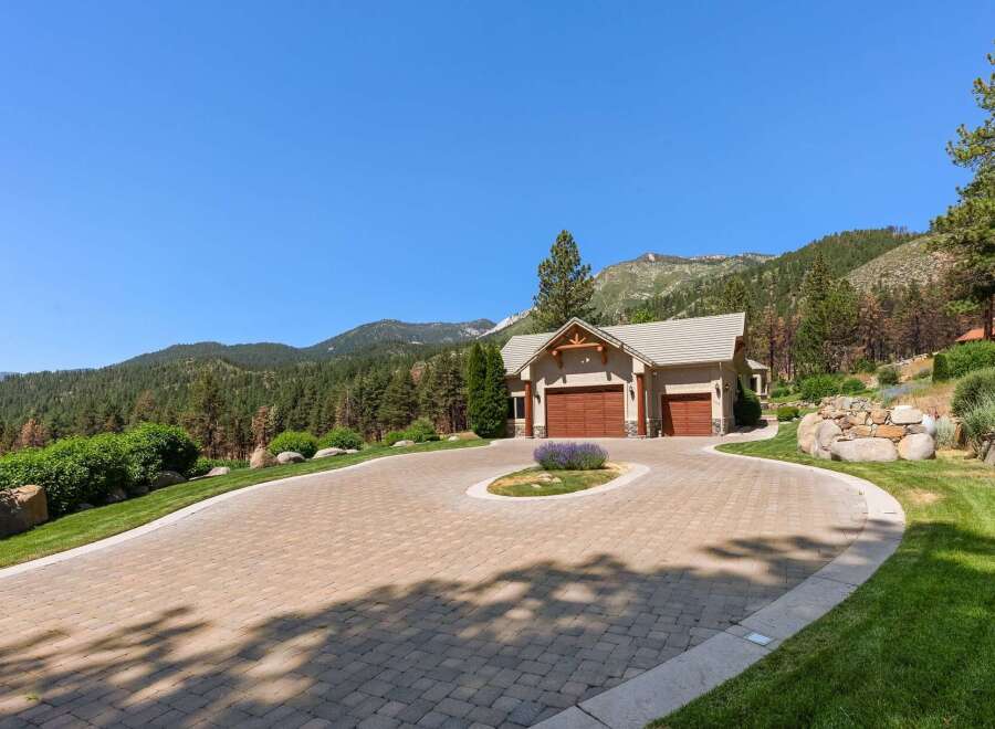 Experience luxury mountain living with this stunning property featuring a spacious paver driveway leading to a charming home with a three-car garage.