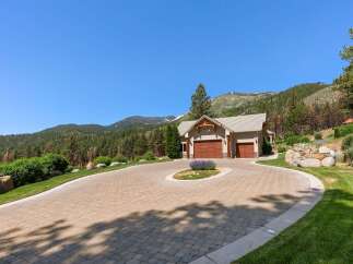 Experience luxury mountain living with this stunning property featuring a spacious paver driveway leading to a charming home with a three-car garage.