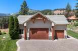 This stunning property features a spacious three-car garage with beautiful wood doors and stone accents, perfect for housing vehicles and storage.