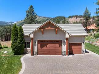 This stunning property features a spacious three-car garage with beautiful wood doors and stone accents, perfect for housing vehicles and storage.