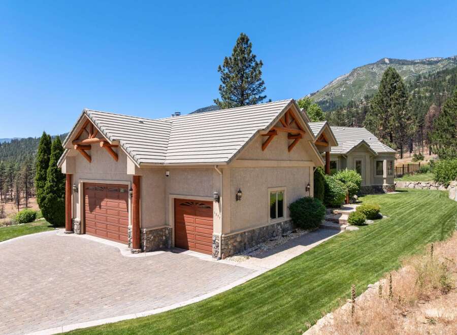 Experience luxury mountain living in this stunning property featuring a spacious three-car garage with a paver driveway and charming stone accents.
