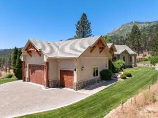 Experience luxury mountain living in this stunning property featuring a spacious three-car garage with a paver driveway and charming stone accents.