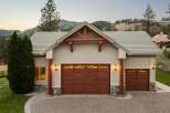 This stunning mountain home features a spacious three-car garage with beautiful wood doors and decorative stone accents.