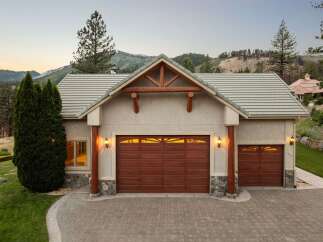 This stunning mountain home features a spacious three-car garage with beautiful wood doors and decorative stone accents.