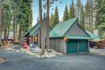 Nestled amidst towering pine trees, this charming mountain home boasts a striking A-frame design with a durable green metal roof.