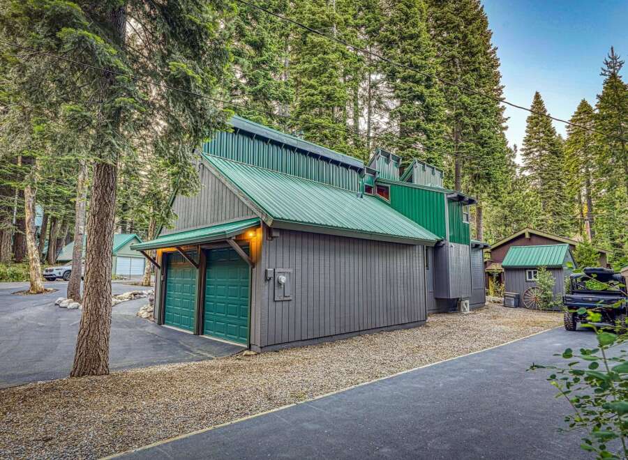 Nestled amidst towering pine trees, this unique property features a striking modern cabin with a vibrant green metal roof and complementary siding.