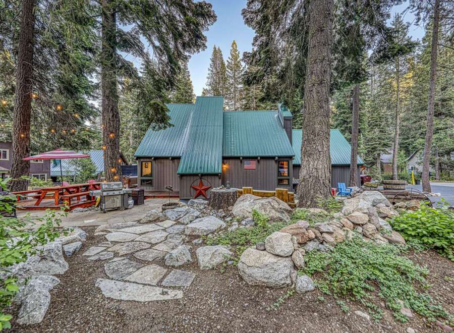 Experience mountain living in this charming cabin featuring a durable green metal roof and rustic brown siding.
