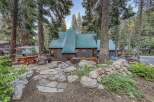 Experience mountain living in this charming cabin featuring a durable green metal roof and rustic brown siding.