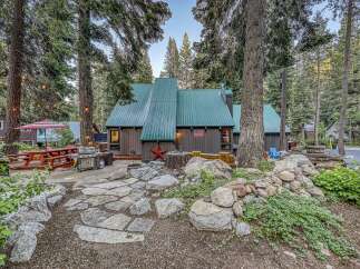 Experience mountain living in this charming cabin featuring a durable green metal roof and rustic brown siding.