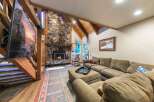 Experience rustic charm in this spacious living room, featuring a grand stone fireplace and exposed wooden beams that create a warm, inviting atmosphere.