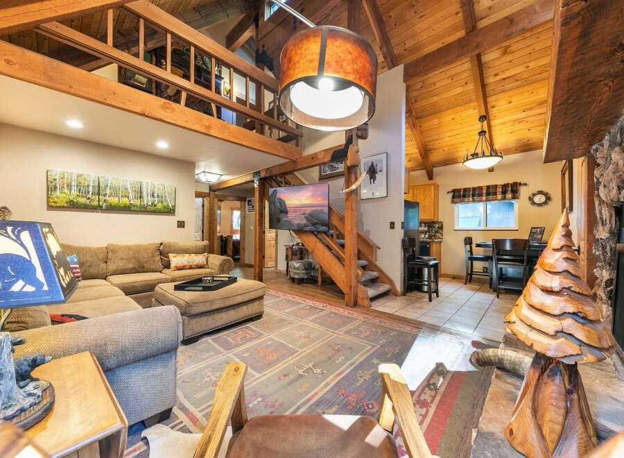 Experience rustic charm in this spacious living area, featuring a large sectional sofa and a unique wooden tree sculpture.
