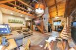 Experience rustic charm in this spacious living area, featuring a large sectional sofa and a unique wooden tree sculpture.