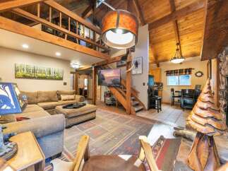 Experience rustic charm in this spacious living area, featuring a large sectional sofa and a unique wooden tree sculpture.