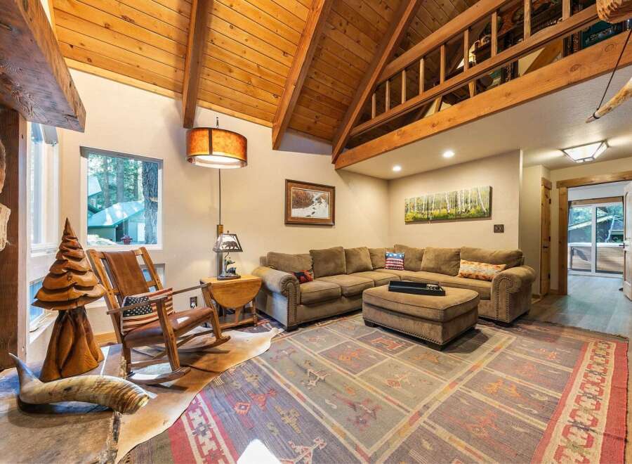 Experience rustic charm in this cozy living room, featuring a vaulted wood-beamed ceiling and a large stone fireplace.