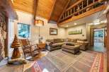 Experience rustic charm in this cozy living room, featuring a vaulted wood-beamed ceiling and a large stone fireplace.