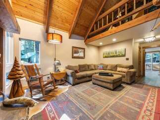 Experience rustic charm in this cozy living room, featuring a vaulted wood-beamed ceiling and a large stone fireplace.