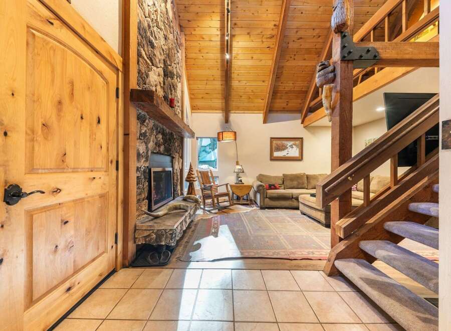 Experience rustic charm in this inviting living space, featuring a grand stone fireplace and soaring vaulted wood ceilings.