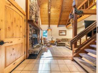 Experience rustic charm in this inviting living space, featuring a grand stone fireplace and soaring vaulted wood ceilings.