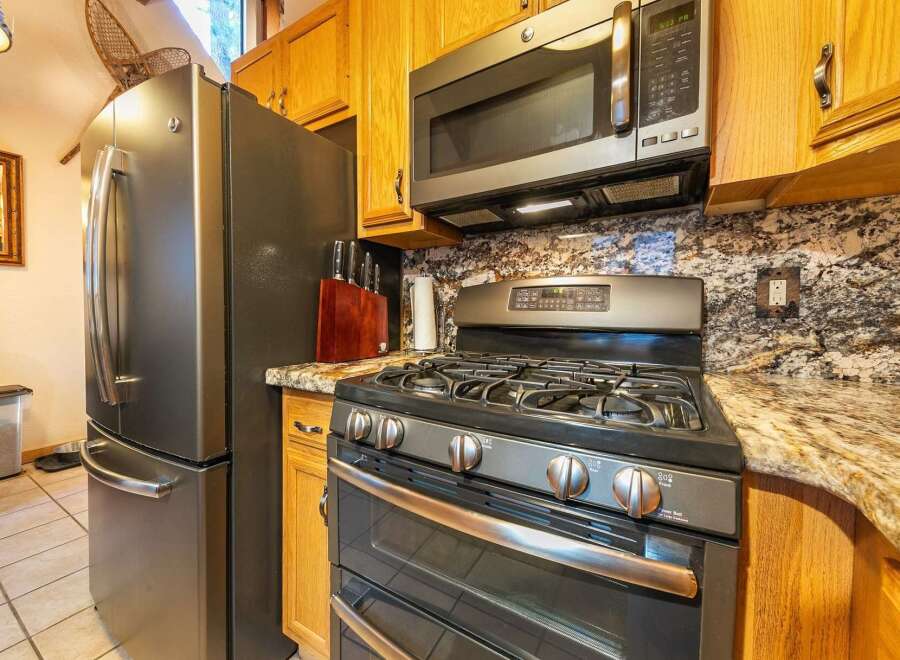 This kitchen boasts a sleek stainless steel refrigerator and a modern gas range, perfect for any home chef.