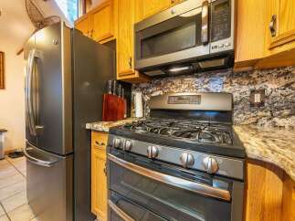 This kitchen boasts a sleek stainless steel refrigerator and a modern gas range, perfect for any home chef.