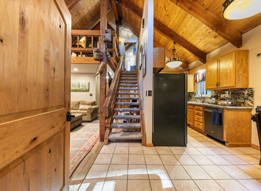 Step into this charming cabin-style home featuring a grand wooden door that opens to a spacious living area and a well-equipped kitchen.