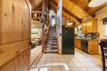 Step into this charming cabin-style home featuring a grand wooden door that opens to a spacious living area and a well-equipped kitchen.