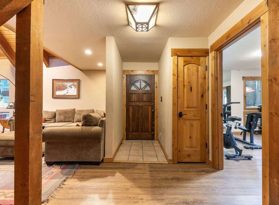 Step into this inviting entryway featuring a rustic wooden front door and a cozy living area with plush seating.