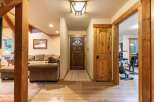 Step into this inviting entryway featuring a rustic wooden front door and a cozy living area with plush seating.